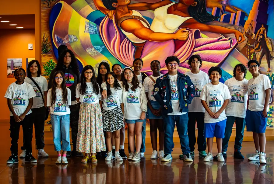 LTBB students gather in front of a colorful community mural.