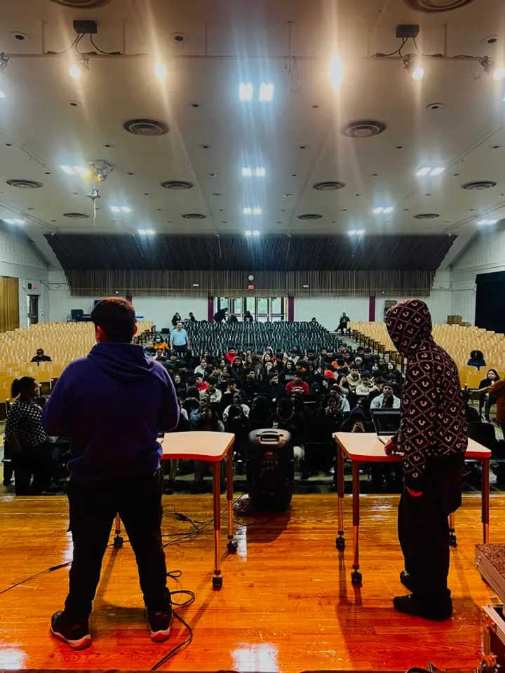 A student volunteer and LTBB facilitator face a school audience during a live beat battle.